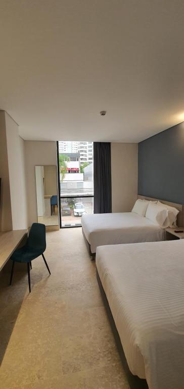 カルタヘナ・デ・インディアスにあるHOTEL RILUX CARTAGENAのベッド2台とデスクが備わるホテルルームです。
