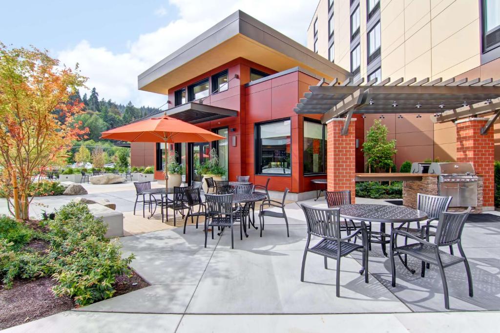 eine Terrasse mit Tischen und Stühlen vor einem Gebäude in der Unterkunft Homewood Suites by Hilton Seattle-Issaquah in Issaquah