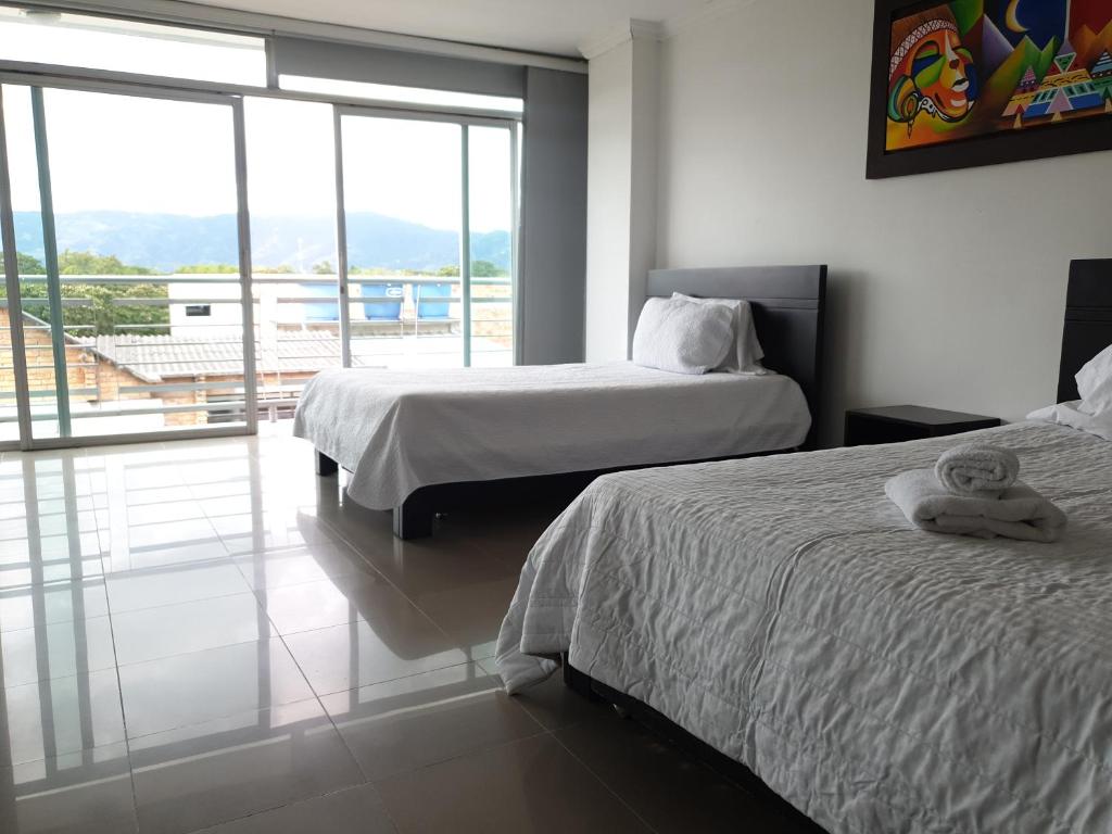 a hotel room with two beds and a balcony at Hotel Andinos Plaza Pitalito in Pitalito