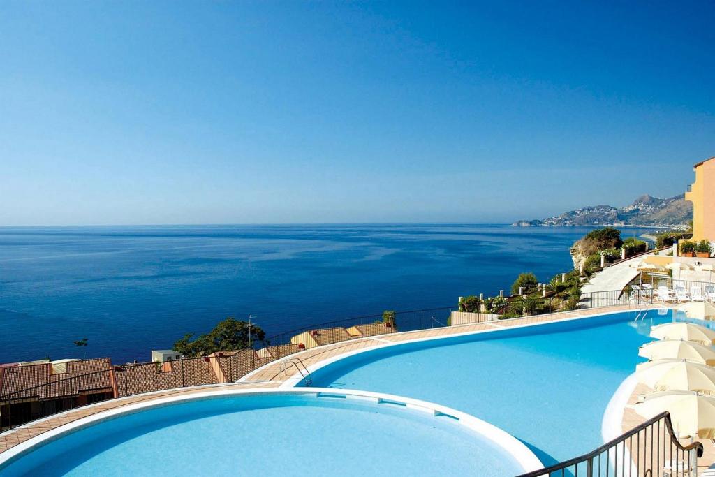 
a view from a balcony overlooking the ocean at Capo Dei Greci Taormina Coast Hotel & SPA in Santa Margherita-Sant'Alessio Siculo
