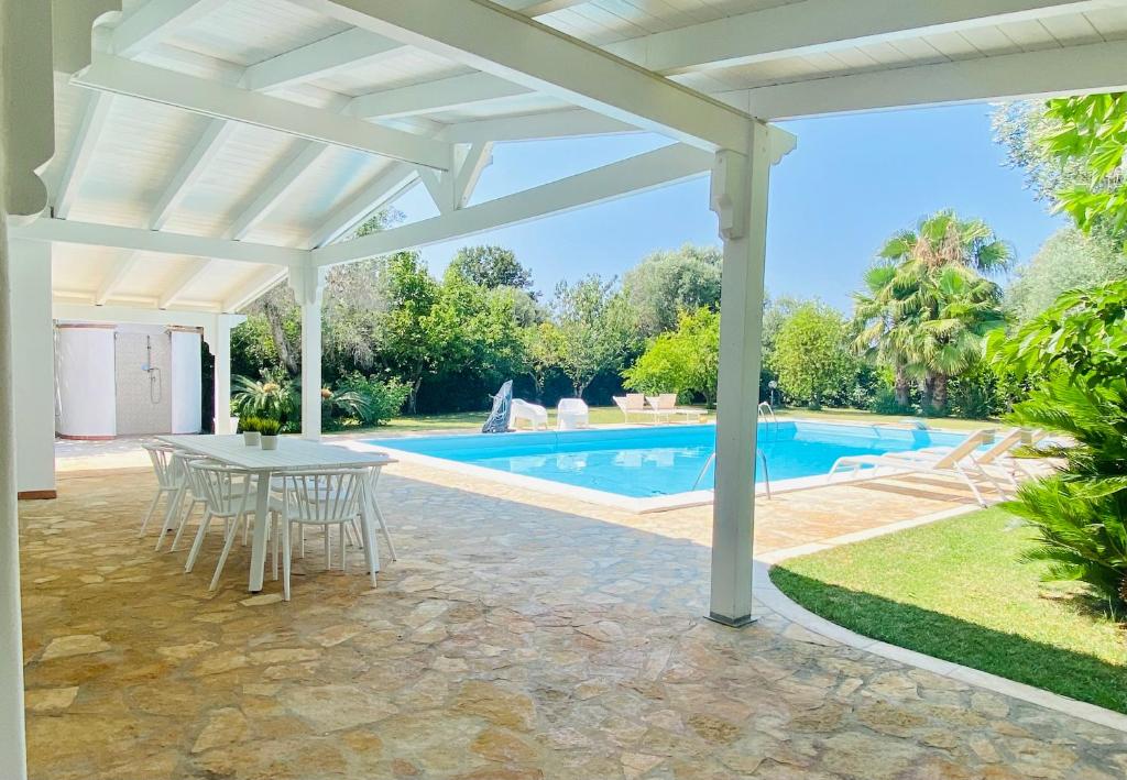 uma pérgola branca com uma mesa e uma piscina em Villa Anita em San Michele Salentino