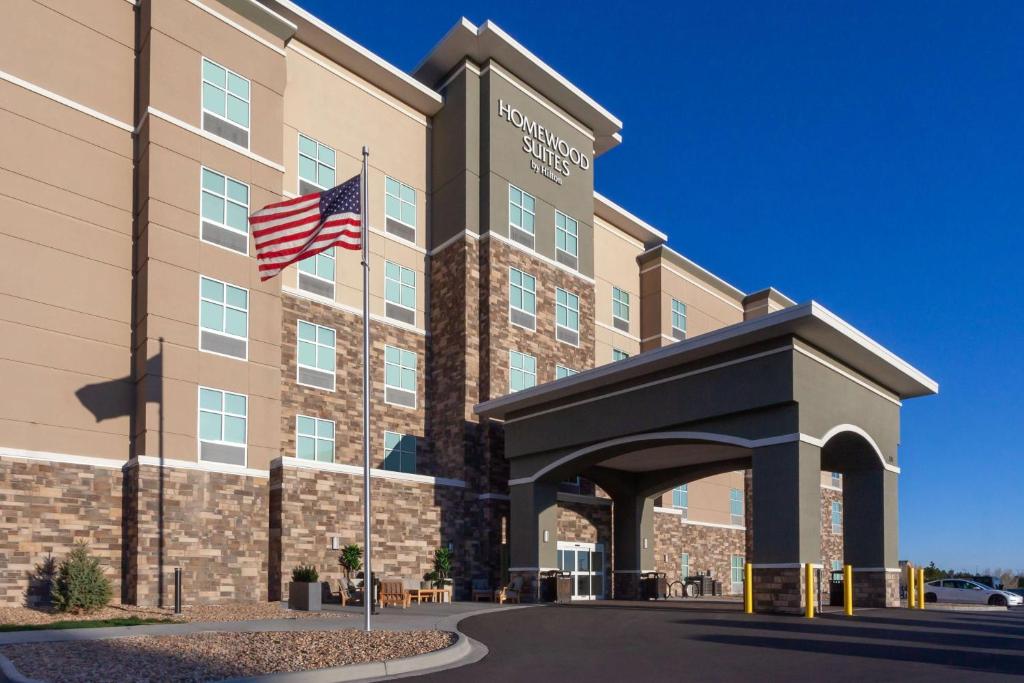 an exterior view of a hotel with an american flag at Homewood Suites By Hilton Broomfield Boulder in Broomfield