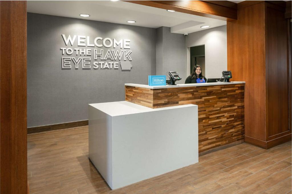 a woman sitting at a welcome to the hawkseyeeyeeyeeye office at Hampton Inn Council Bluffs in Council Bluffs