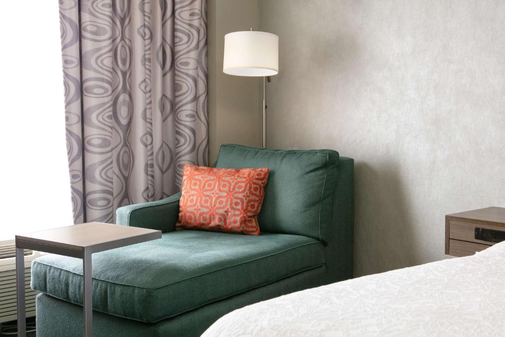 a green chair with a orange pillow in a hotel room at Hampton Inn Council Bluffs in Council Bluffs