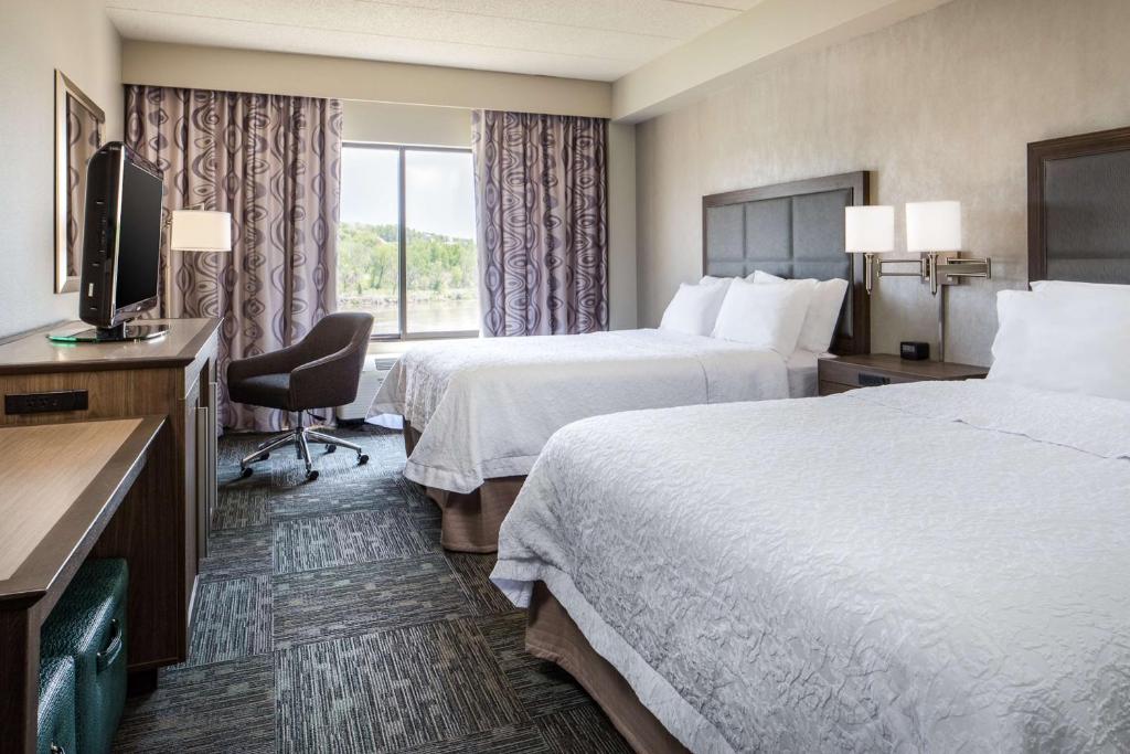 a hotel room with two beds and a television at Hampton Inn Council Bluffs in Council Bluffs