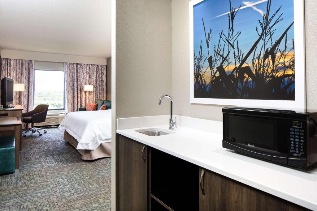 a hotel room with a sink and a room with a bed at Hampton Inn Council Bluffs in Council Bluffs