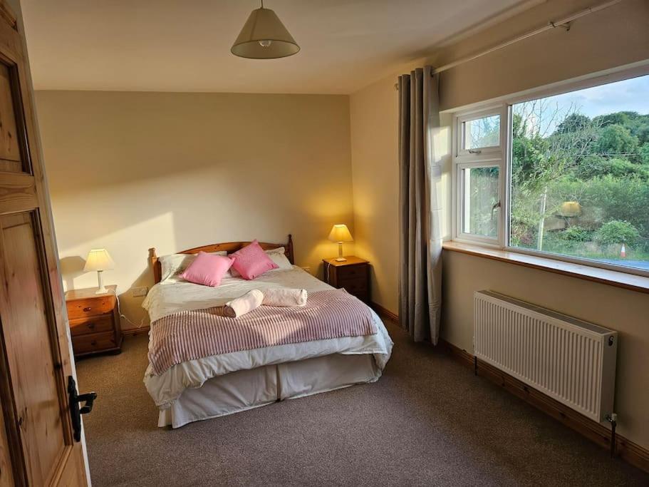 um quarto com uma cama com almofadas cor-de-rosa e uma janela em Hillview House 