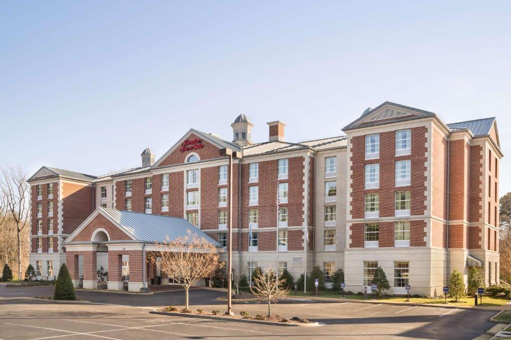 a large brick building in front of a parking lot at Hampton Inn & Suites Williamsburg-Central in Williamsburg