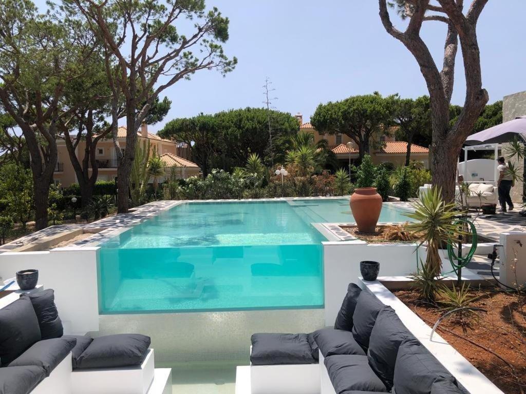 una piscina en un patio con sillas y árboles en CASA DOS CATOS, en Praia Verde