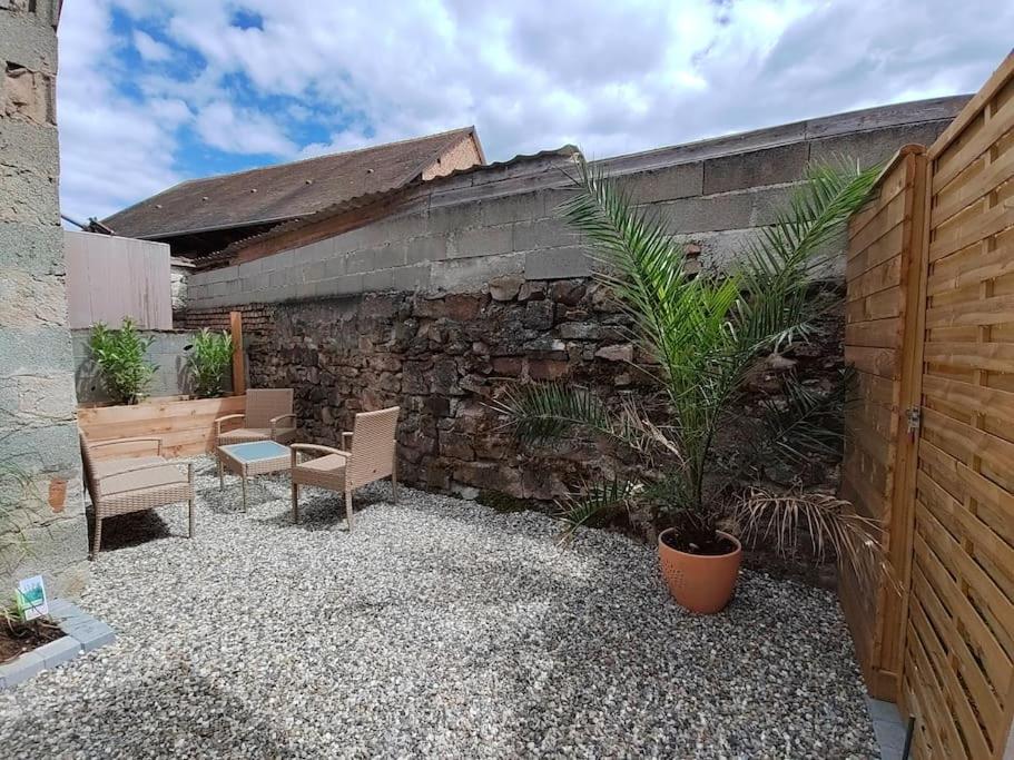 un patio con 2 sillas y una pared de piedra en Appartement indépendant avec extérieur en Epfig