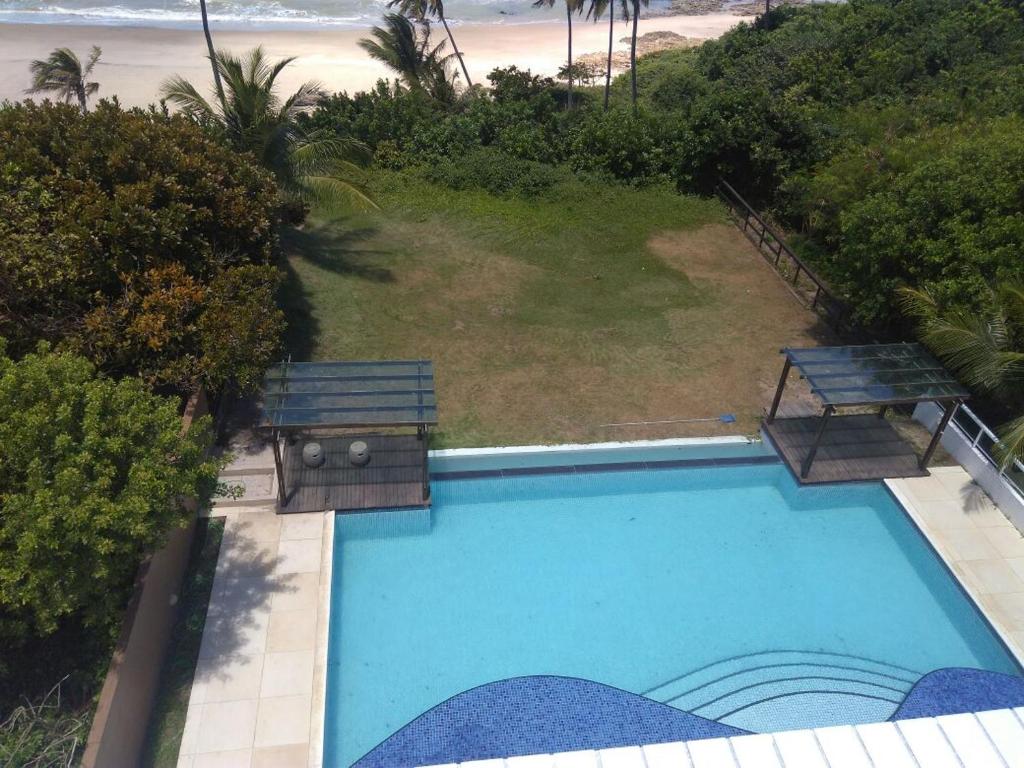 Draufsicht auf ein Schwimmbad mit Bänken und den Strand in der Unterkunft Flat de frente ao mar in Conde