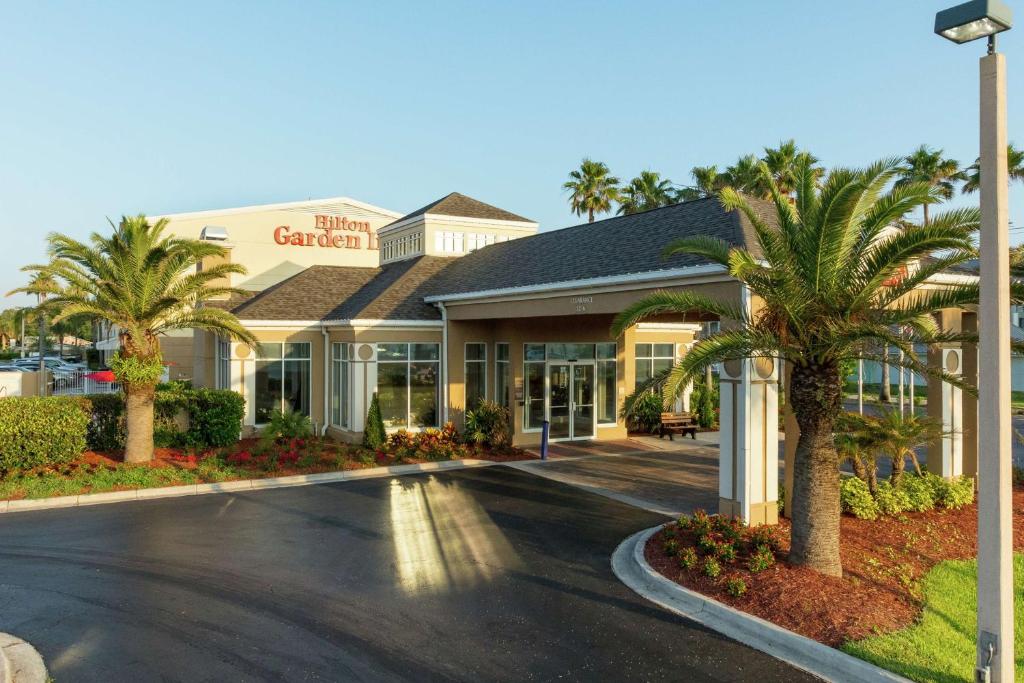 a hotel with palm trees in front of a building at Hilton Garden Inn Saint Augustine Beach in Saint Augustine Beach
