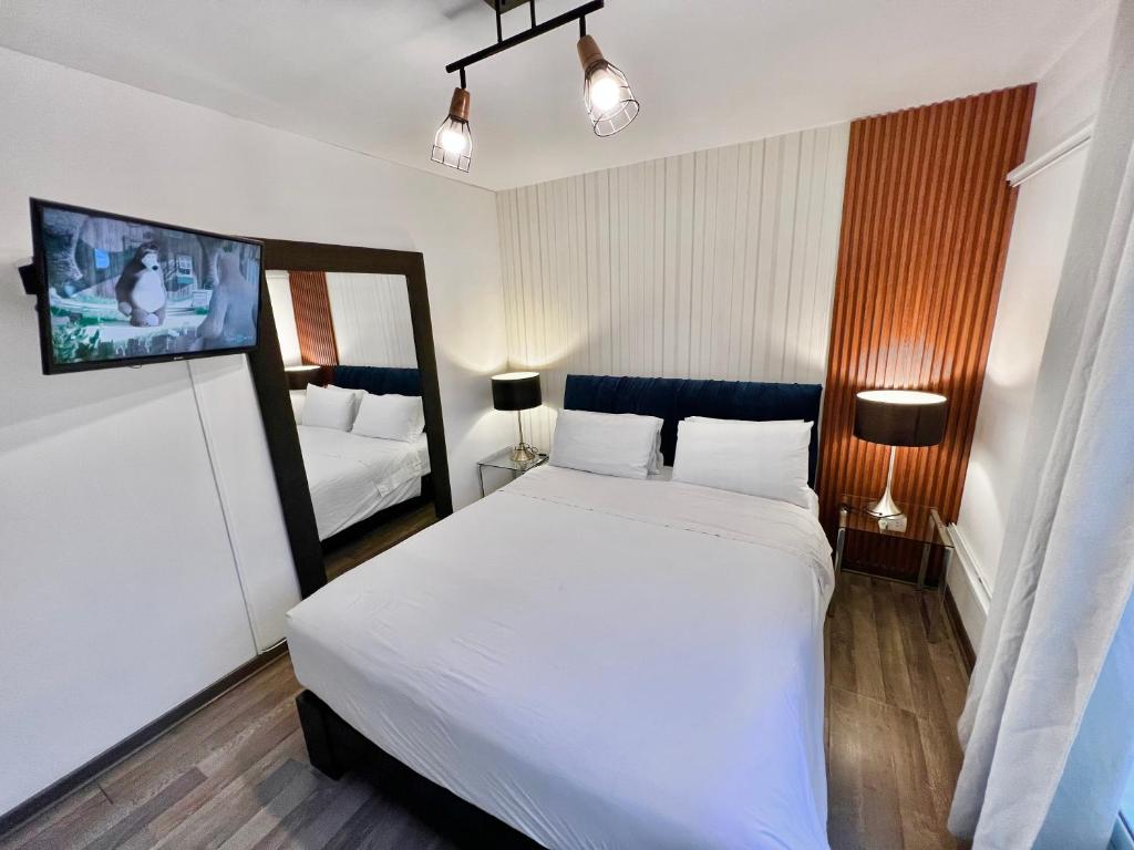 1 dormitorio con 1 cama blanca y TV en la pared en CUADRUPLEX Con TERRAZA, en Lima