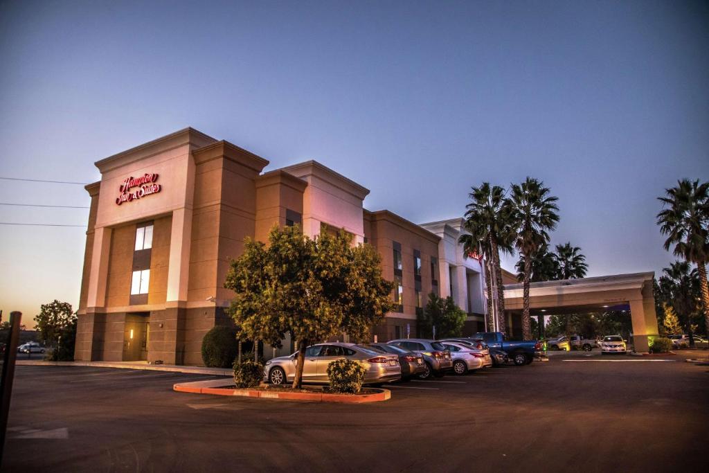 een hotel met auto's geparkeerd op een parkeerplaats bij Hampton Inn & Suites Lathrop in Lathrop