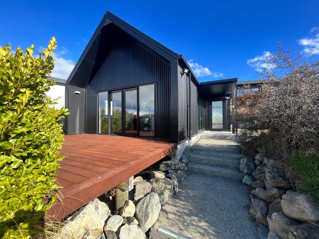 a modern house with a wooden deck and rocks at Mary Hut in Lake Tekapo