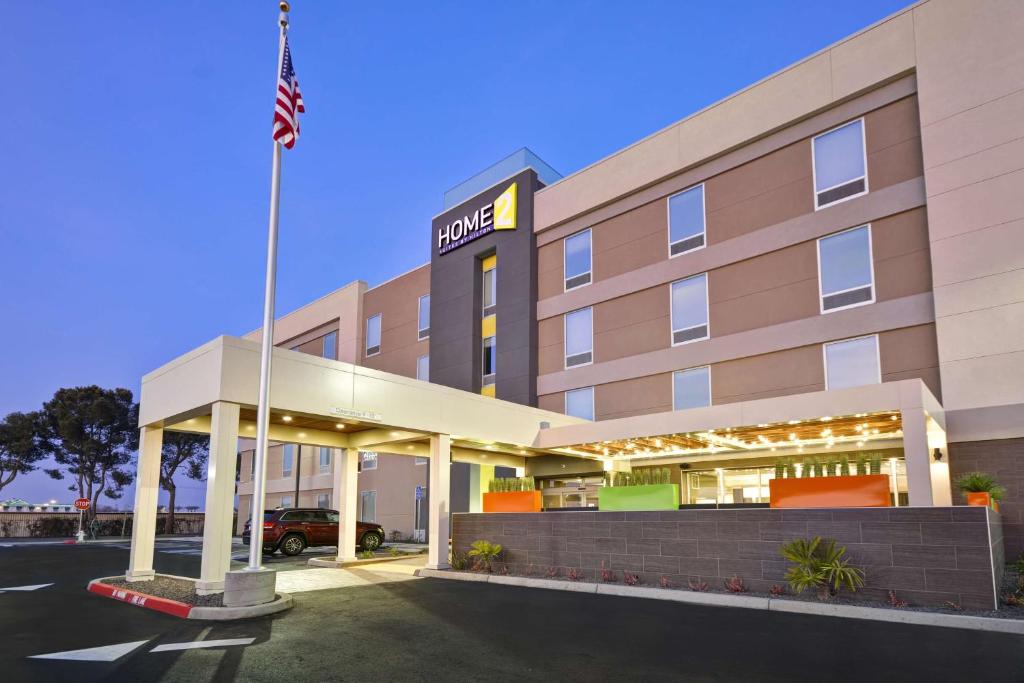 an exterior view of a hotel with an american flag at Home2 Suites By Hilton Hanford Lemoore in Hanford