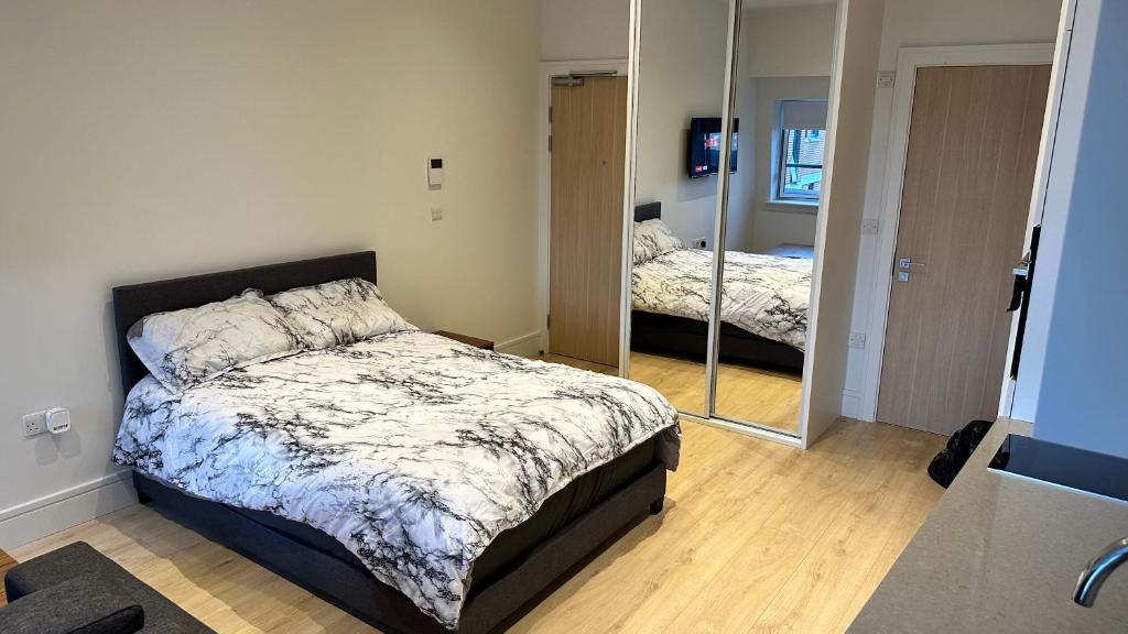 een slaapkamer met een bed en een spiegel bij lovely full studio apartment in Ilford