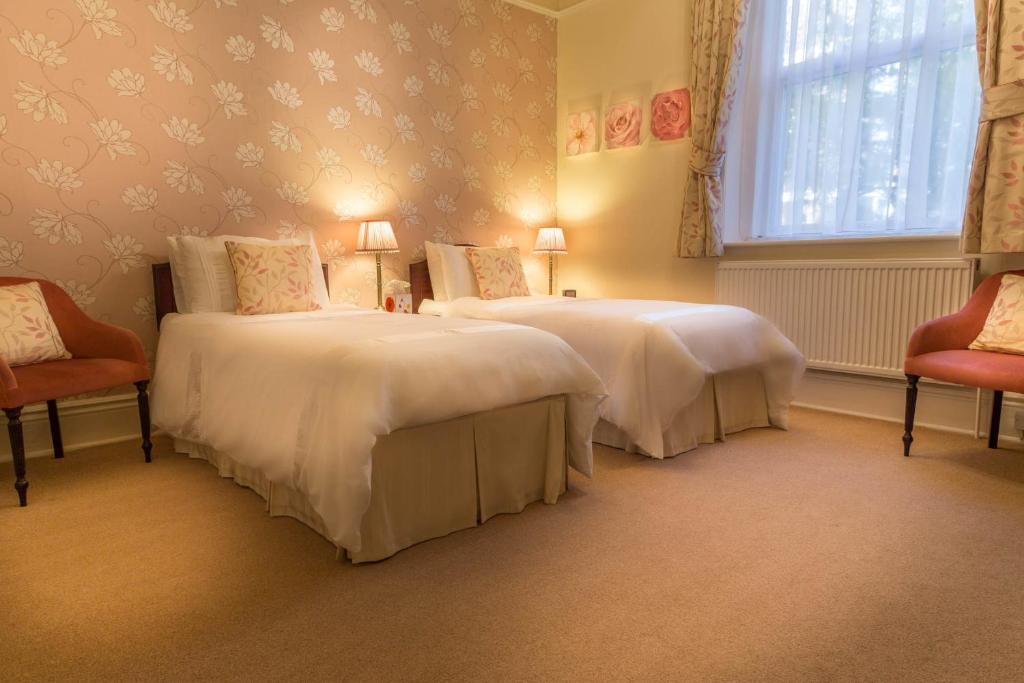 two beds in a room with two chairs and a window at Balincourt in Bournemouth
