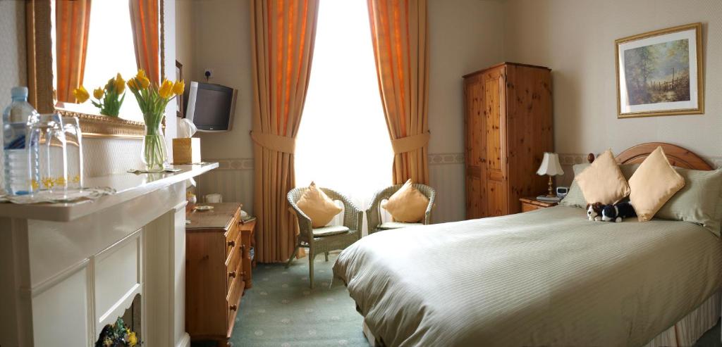 a bedroom with a bed and two chairs and a television at Balincourt in Bournemouth