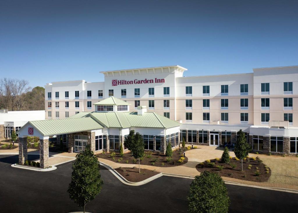 Hilton Garden Inn Olive Branch, Ms في اوليف برانش: مبنى مستشفى أبيض كبير مع موقف للسيارات
