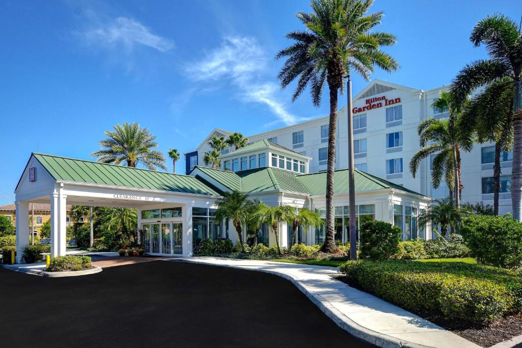 a hotel with palm trees in front of a building at Hilton Garden Inn Fort Myers in Fort Myers