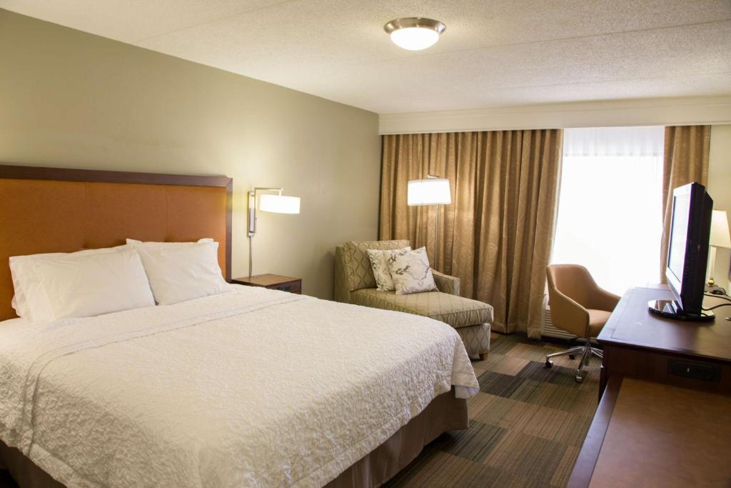 a hotel room with a bed and a chair and a television at Hampton Inn & Suites Albany-Downtown in Albany