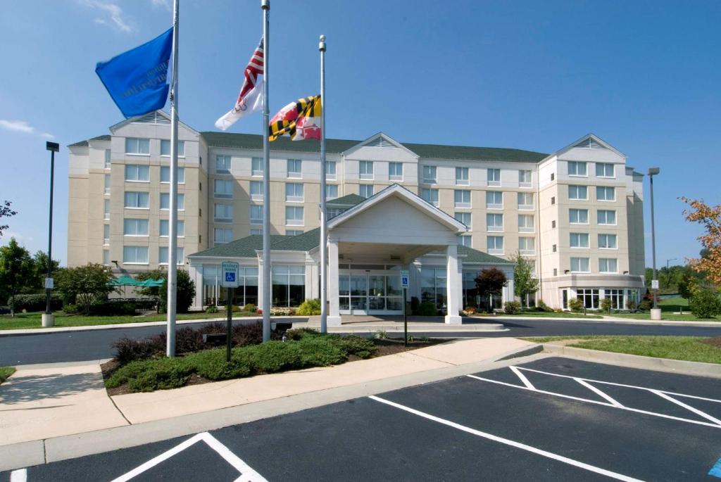 ein Hotel mit Flaggen vor einem Parkplatz in der Unterkunft Hilton Garden Inn Owings Mills in Owings Mills