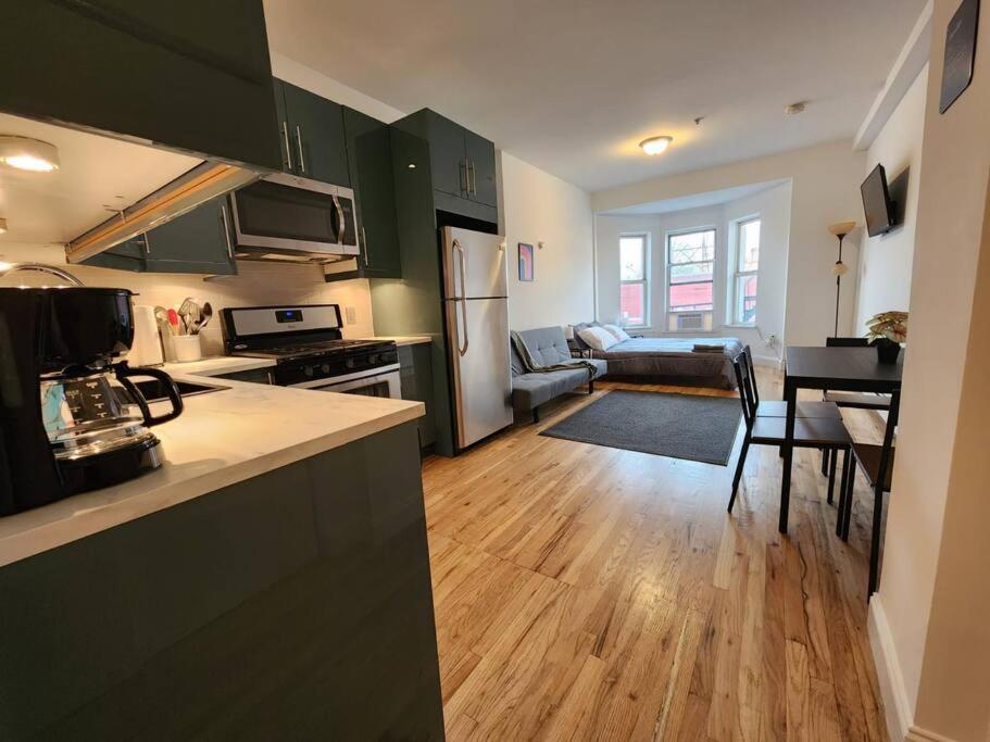 a kitchen with green cabinets and a living room at Deluxe Studio minutes from NYC! in Union City