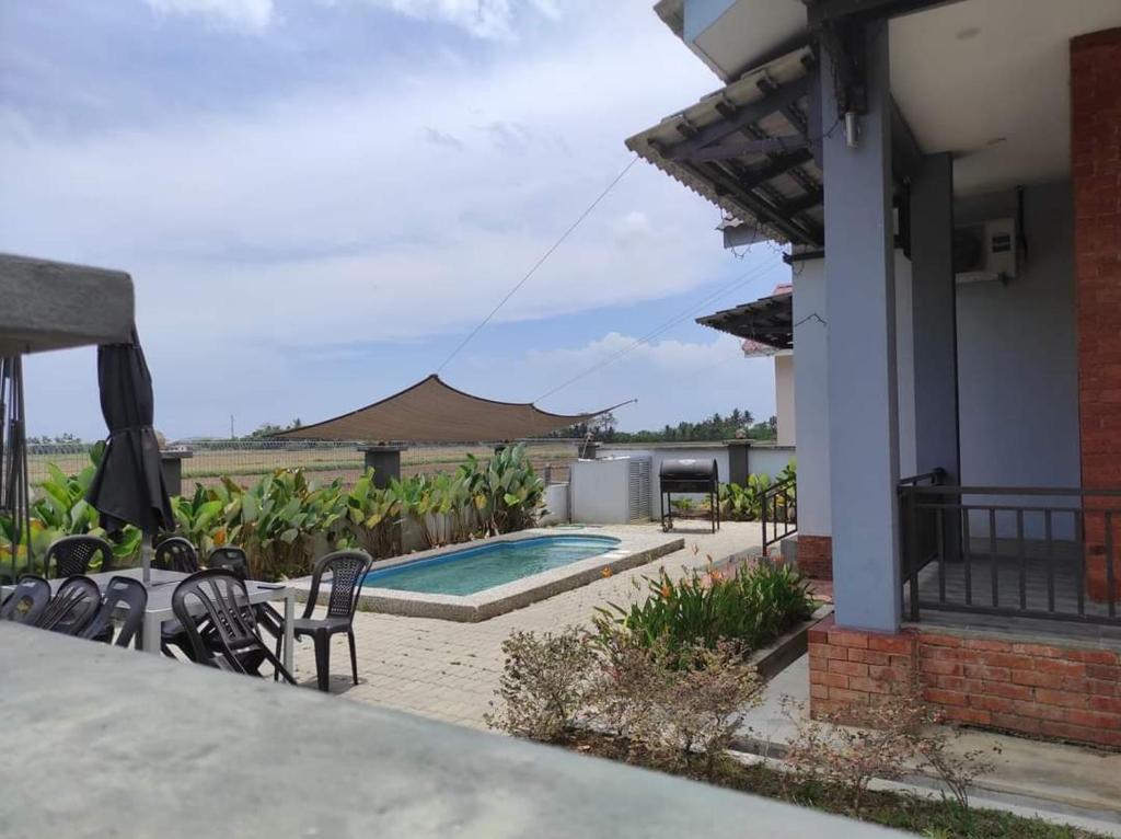 a backyard with a swimming pool and chairs and a house at Murni Inn Kampung Perigi in Yan