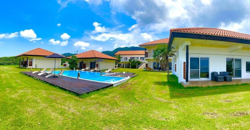 a house with a large yard with a swimming pool at エコヴィレッジ西表 Eco Village Iriomote in Iriomote