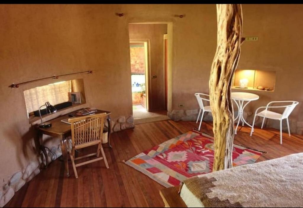 een woonkamer met een bureau en een tafel met stoelen bij Off the Grid Lakauta Lodge in San Pedro de Atacama