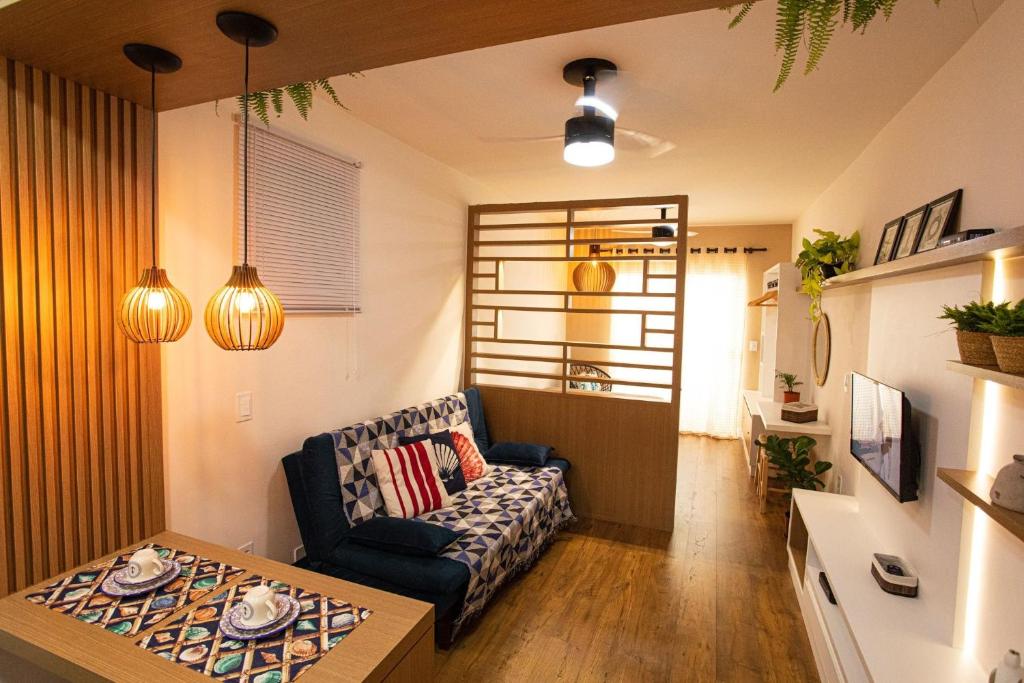 een woonkamer met een bank en een tafel bij Areia Preta Park Studio | Salma Haddad in Guarapari