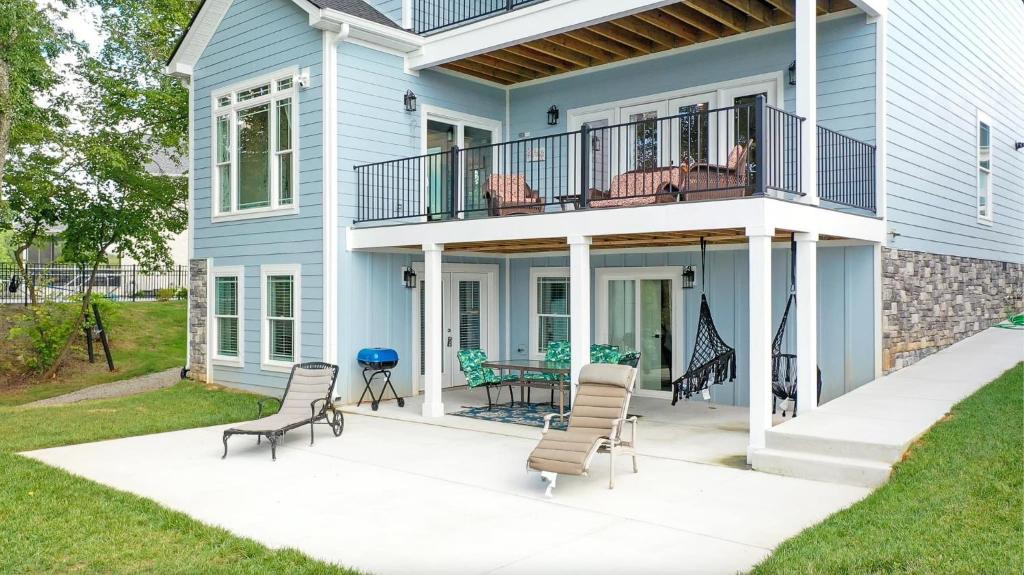 una casa blu con terrazza e sedie su un patio di Luxurious LakeHouse NewBuild TimsFord 4BR4BTH a Winchester