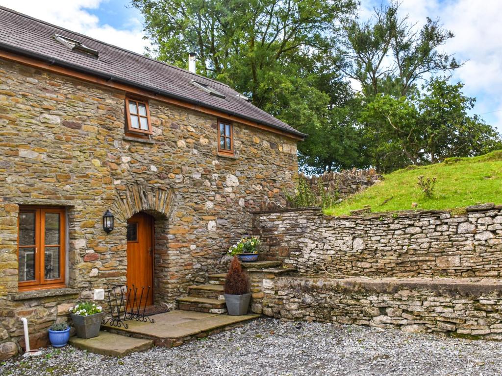 a stone house with a stone wall and a door at Llandremor Fawr Cottage in Llanedy