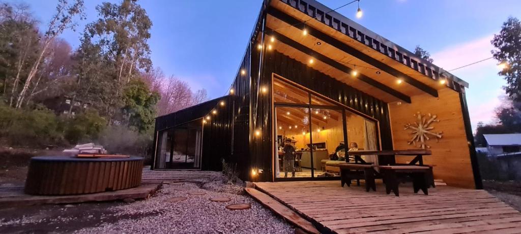 una casa con una terraza de madera con luces. en Cabaña en el bosque-Termas de Chillán, en Recinto