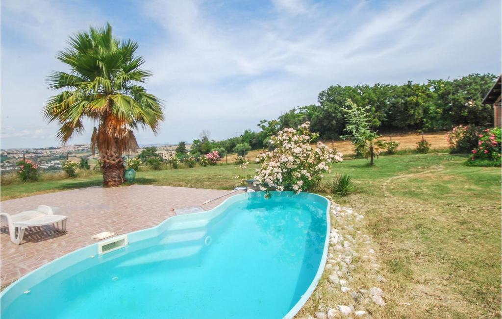 una piscina azul en un patio con una palmera en Lovely Home In Fermo With Kitchen, en Fermo