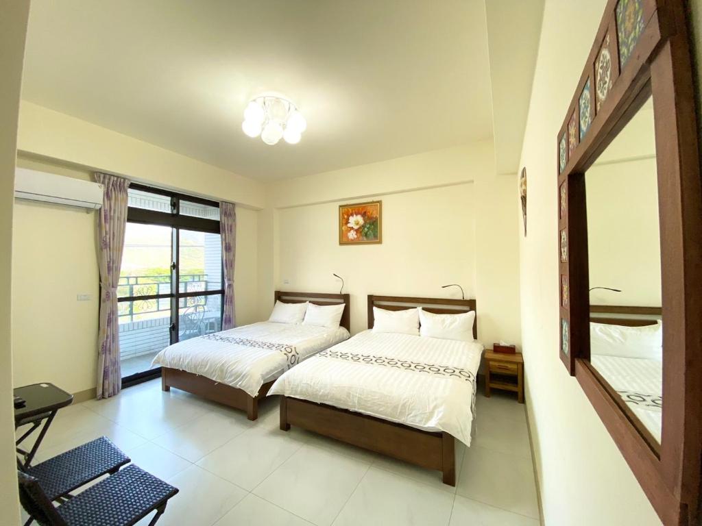 a bedroom with two beds and a large window at Huitaro Homestay in Yuli