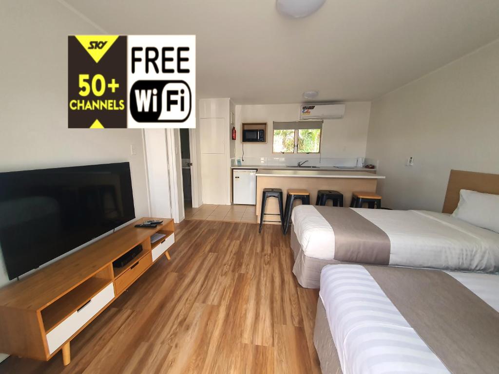 a hotel room with two beds and a flat screen tv at Ocean Inn Motel in Auckland