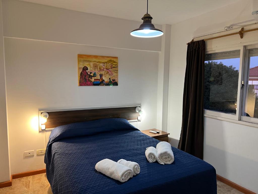 Un dormitorio con una cama azul con toallas. en DEPARTAMENTO AHNEN CORDOBA - Cerca Instituto Cardiologico, Ferial Cordoba, Hospital Privado Cerro y Sanatorio Allende en Córdoba