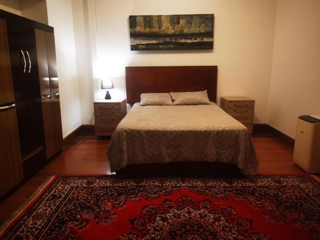 um quarto com uma cama e um tapete vermelho em La Casona Hospedaje em Lima