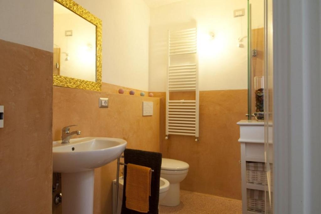 W łazience znajduje się umywalka, toaleta i lustro. w obiekcie Riz Guest House w mieście Montesano Salentino