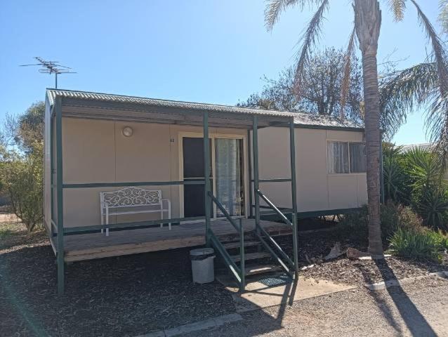 a tiny house with a porch and a bench at Sunraysia Holiday Park in Mildura