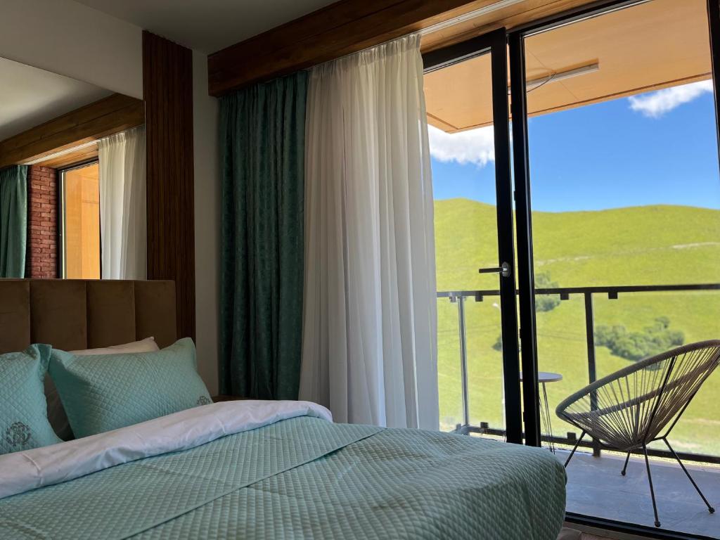 a bedroom with a bed and a balcony with a view at Luxury apartment with specticular views in Gudauri