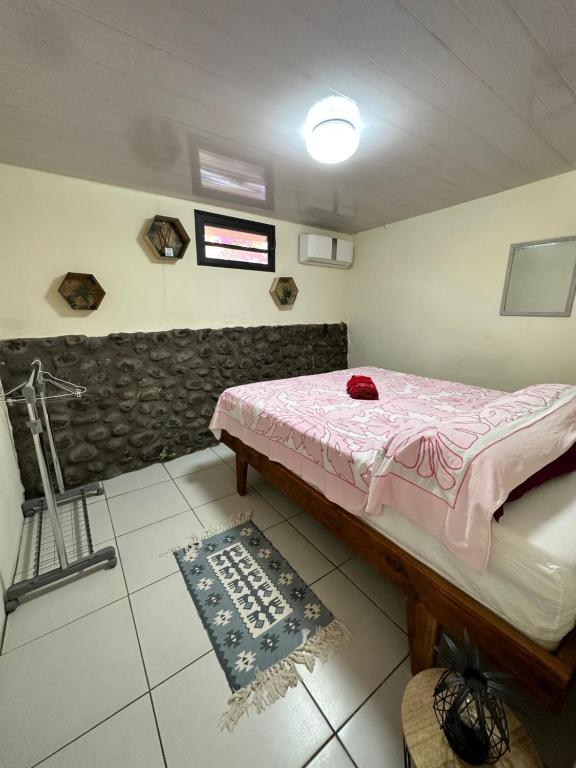 een kleine kamer met een bed en een tapijt bij Kahea Ragni in Punaauia