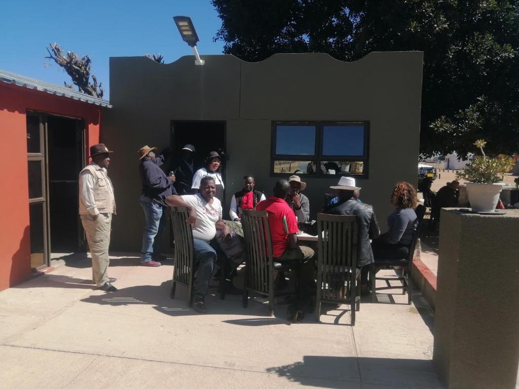 a group of people sitting in chairs outside a building at Okahatjipara Lodge 