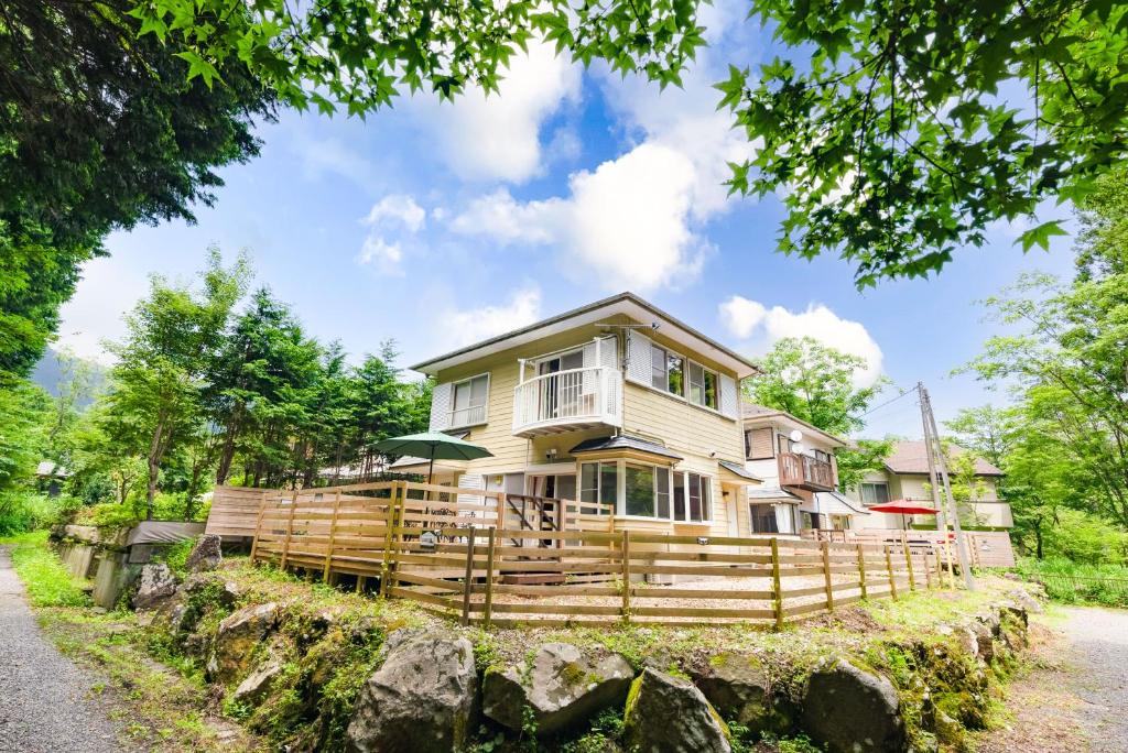ein großes Haus mit einem Zaun drum herum in der Unterkunft Green Oasis Cottage Hakone Sengokuhara - グリーンオアシスコテージ箱根仙石原 in Sengokuhara