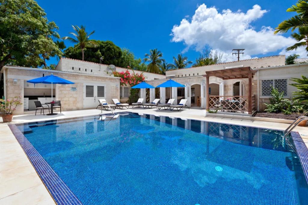 a swimming pool with chairs and umbrellas next to a house at Todmorden by Blue Sky Luxury in Saint Peter