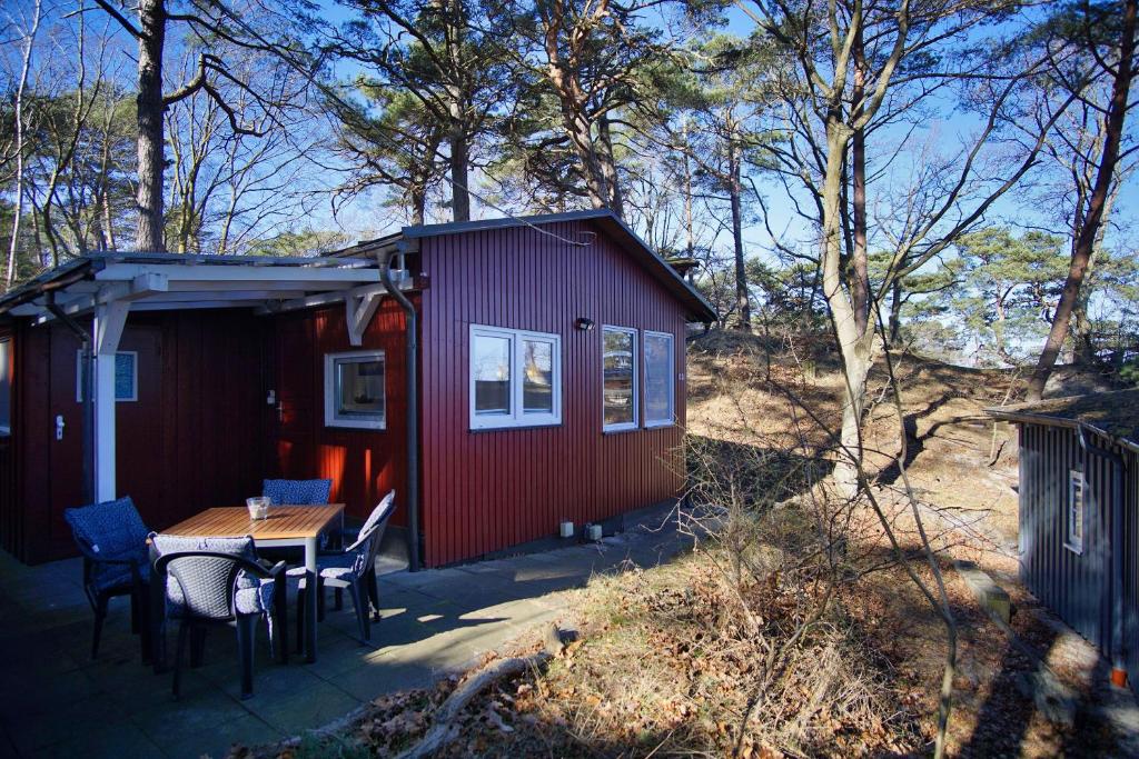 a small red cabin with a table and chairs at Dünenchalet Nr 49 in Göhren