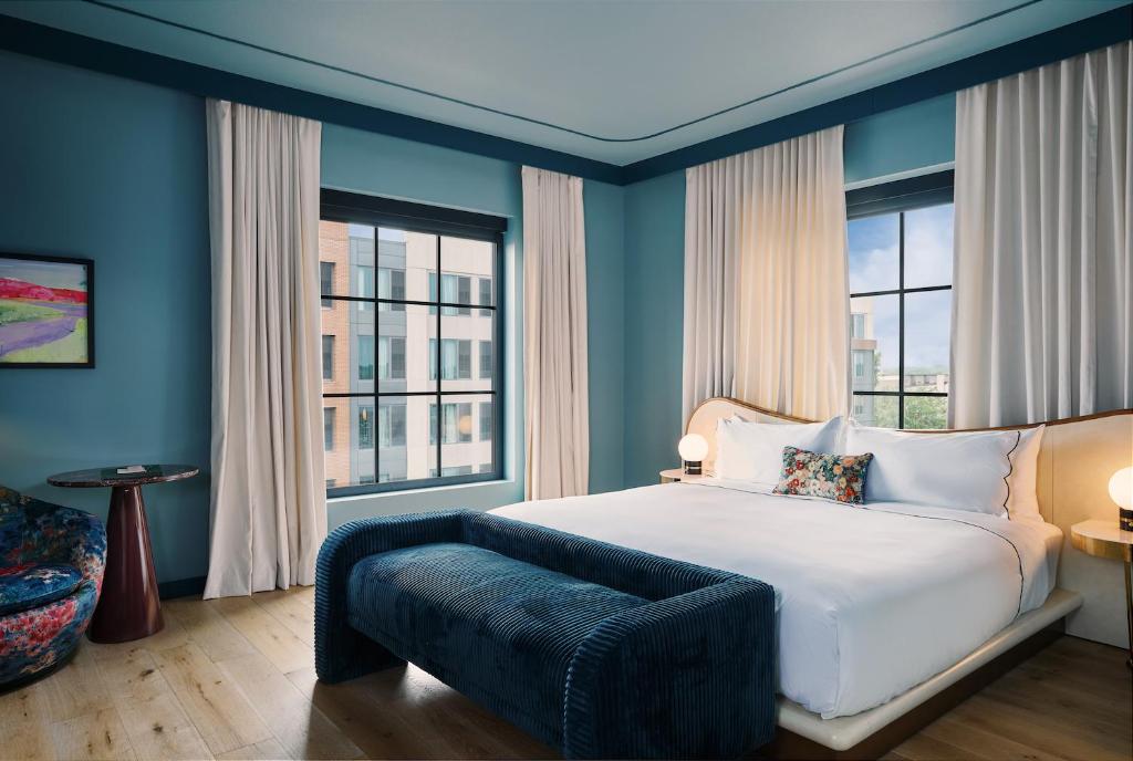 a bedroom with a white bed and two windows at Hotel Genevieve in Louisville