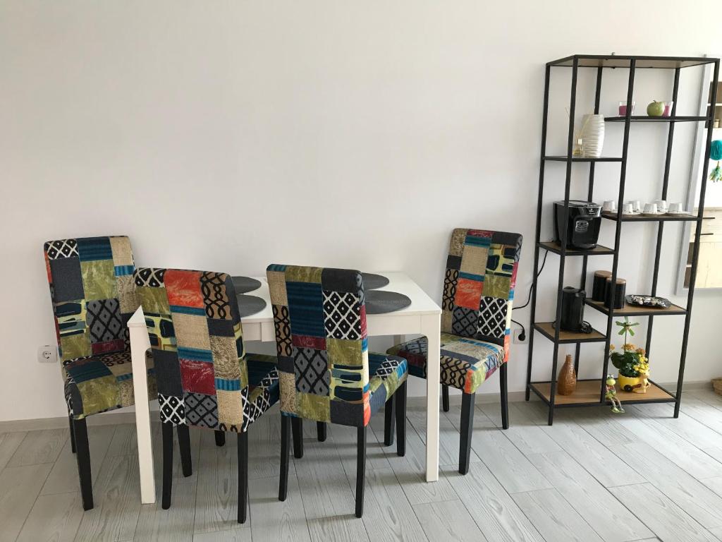 a dining room table with four chairs and a shelf at CaSa Stai in Mangalia